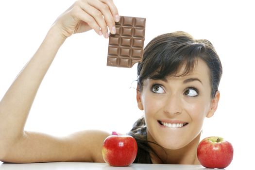 Young woman torn between a chocolate bar and fresh apple