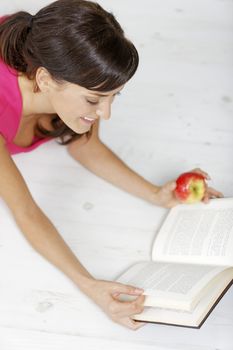 Young woman lying on the floor at home reading a book