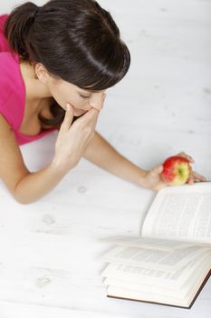 Young woman lying on the floor at home reading a book