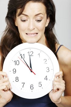 Young woman holding clock face expressing anticipation