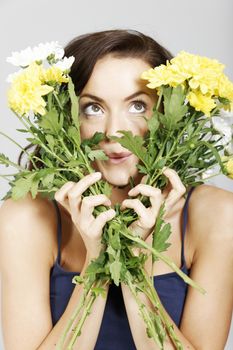 Young woman looking through two bunches of flowers