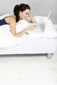 Young woman using her laptop in bed