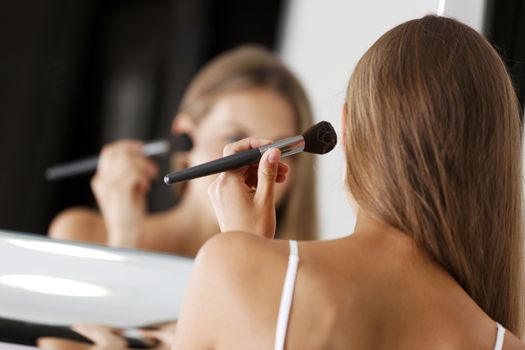 Attractive young woman in underwear applying make up in bathroom.