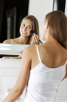 Attractive young woman in underwear applying make up in bathroom.