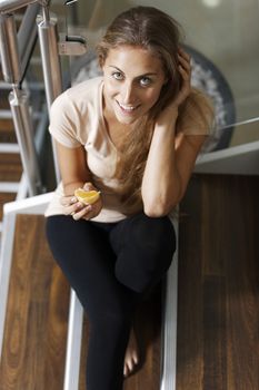 Beautiful young woman eating fruit on steps taking a break.