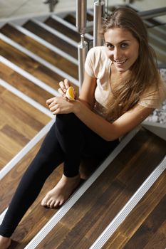 Beautiful young woman eating fruit on steps taking a break.