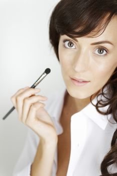 Attractive young woman applying make up using a brush