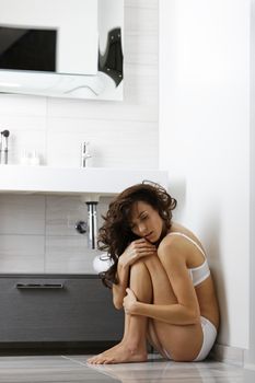 Attractive young woman sitting in her bathroom smiling