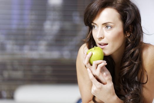 Beautiful young woman relaxing with an apple at home.