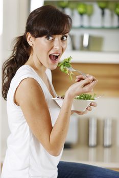 Young woman enjoying a fresh salad in her kitchen