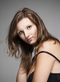 portrait of a young beautiful woman with brown hair against gray background