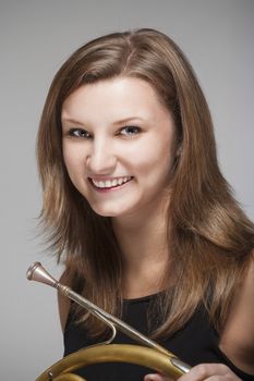 portrait of young female musician with concert french horn in black dress