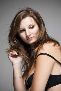 portrait of a young beautiful woman with brown hair against gray background