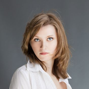 portrait of a young beautiful woman with brown hair against gray background