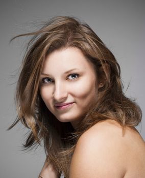 portrait of a young beautiful woman with brown hair against gray background