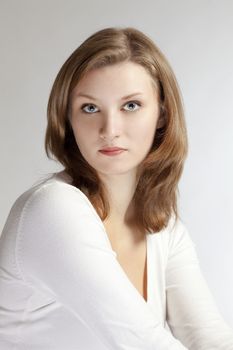 portrait of a young beautiful woman with brown hair against light gray background