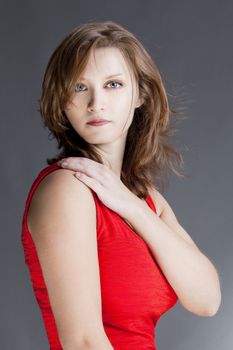 portrait of a young beautiful woman in red dress against gray background