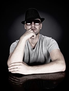 man in hat and sunglasses sitting behind desk looking at camera