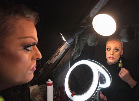 Serious drag queen in front of mirror with lamp