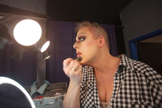 Man in dressing room preparing face for drag queen show