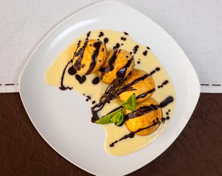 tasty dessert with chocolate, sweet sauce, cakes and mint on a white plate