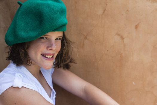 Young girl happy smiling wearing green beret hat.