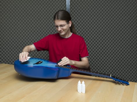 Young guitarist cleaning and polishing his guitar ( Series with the same model available)