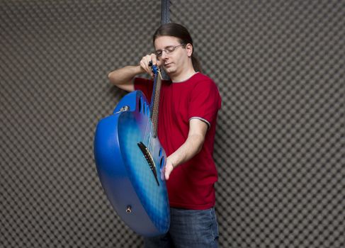 Guitar technician checking the adjustment of a blue electro-acoustic guitar's neck ( series with the same model available)