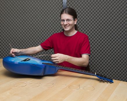 Smiling guitarist changing the guitar strings ( Series with the same model available)