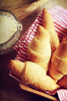 Croissant with milk and wheat on rustic wooden table