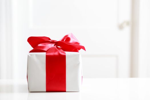 Gift box with red bow on the white table