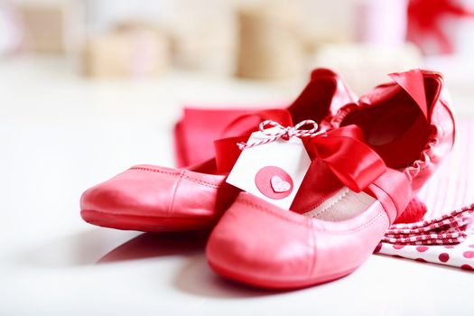 Gift wrapped girls red shoes with ribbon and heart tag