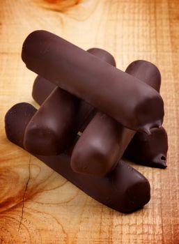 Stack of Ice Cream Sticks Glazed in Dark Chocolate closeup on Wooden background