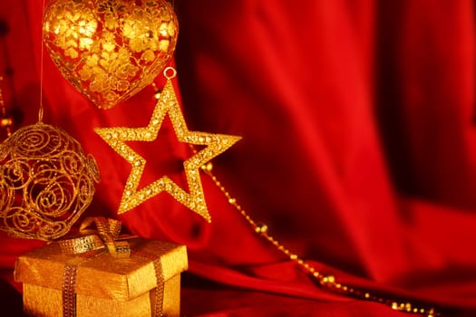 Golden christmas decoration and gift on red fabric background