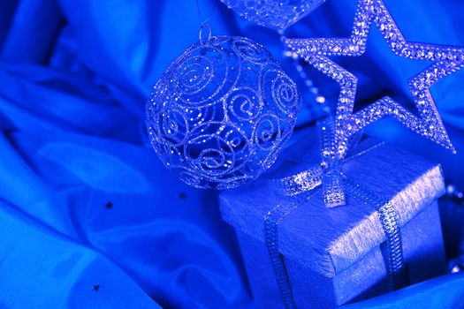 Silver christmas decoration and gift on blue fabric background