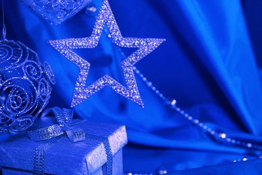 Silver christmas decoration and gift on blue fabric background