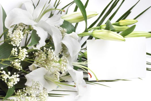 White lily flowers and post card over white background