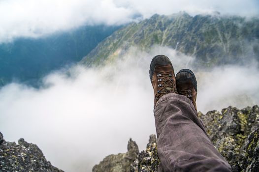 Hiking boots of a hiker while taking a rest in the high mountains over the clouds