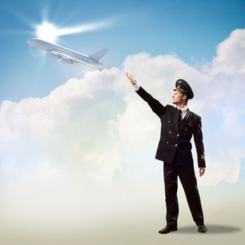 pilot in the form of extending a hand to a flying airplane on the background of clouds and sun