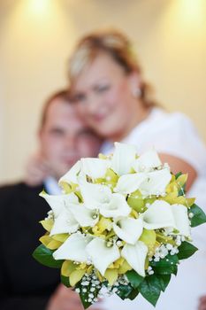 beautiful young wedding couple, bride with her groom and wedding bouquet, focus to wedding bouquet