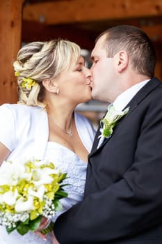 beautiful young wedding couple outdoor, bride with bouquet kissing  her groom