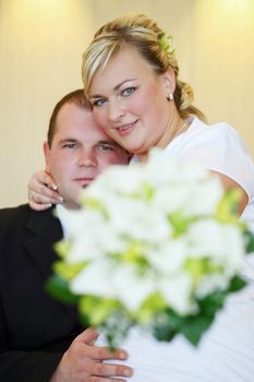 beautiful young wedding couple, bride with her groom and wedding bouquet, focus to bride