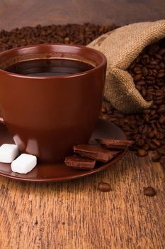 Cup of coffee and fresh coffee beans on a wooden background