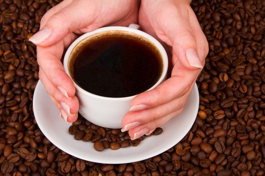 Woman holding hot cup of coffee, on coffee beans background