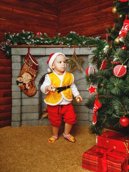 Child standing near Christmas tree beneath which lie gifts