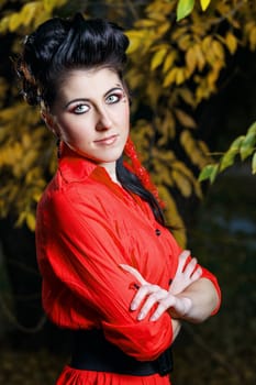 Young attractive girl in red shirt and with makeup close-up portrait in autumn park