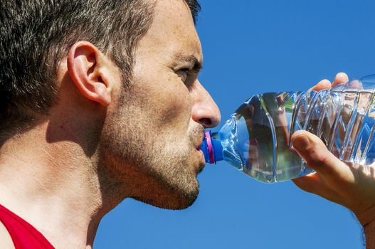 Man is drinking water against blue sky