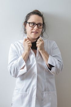 thirtie something brunette woman wearing a lab coat holding up her collar