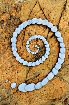 Spiral of white pebbles on the sea boulder