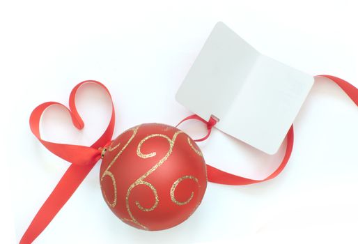 Heart shaped ribbon bow attached to christmas bauble and blank gift tag card 